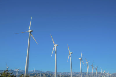 Low angle view of windmill against clear blue sky