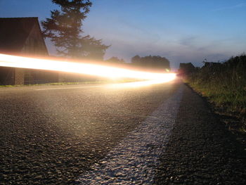 Illuminated street light against sky at night