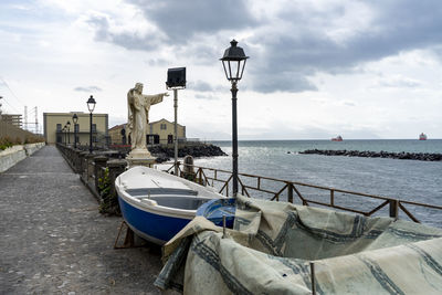 Boats moored on street by sea against sky