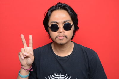 Portrait of young man standing against red background