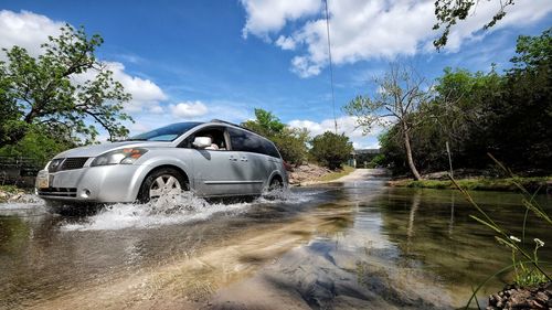 Car moving on flooded road against sky