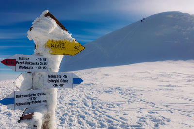 Information sign on snow covered mountain against sky