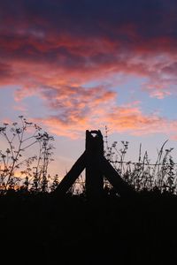 Silhouette plants on field against orange sky