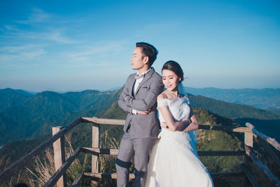 Young couple standing on mountain against sky