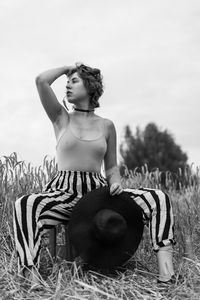 Young woman looking away while sitting on field