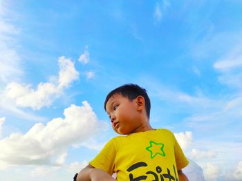 Low angle view of boy against yellow sky