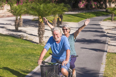 Cheerful senior couple riding bicycle in park