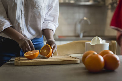 Young woman cutting oranges, partial view