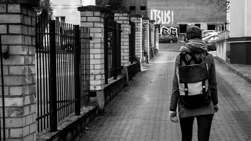 Rear view of person with backpack walking on street