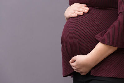 Midsection of woman standing against red background