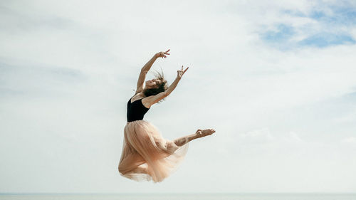 Woman dancing over sea against sky