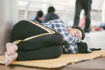 Beggar sleeping on bridge in city