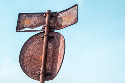 Low angle view of old rusty metal against blue sky