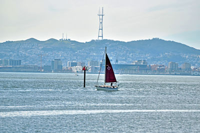 Sailboat on sea against sky in city
