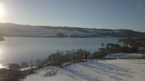 Scenic view of lake by snowcapped mountains against sky