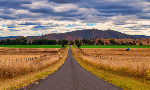 Road amidst field against sky