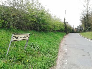 Empty road leading towards grassy field