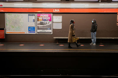 Rear view of people standing at railroad station