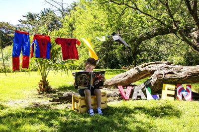 Young man sitting on clothesline by tree