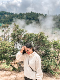 Young woman using phone while standing on land