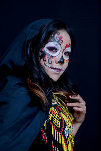 Portrait of smiling young woman against black background