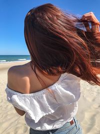 Rear view of woman with tousled hair at beach