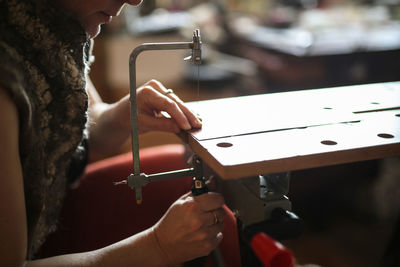 Master in the home workshop saws out a piece of copper metal with a jigsaw, concept creativity 