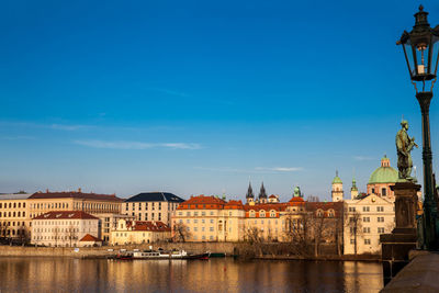 Buildings at waterfront against blue sky