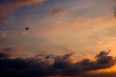 Low angle view of airplane flying against cloudy sky