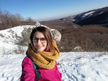 Portrait of smiling young woman standing on snow covered landscape