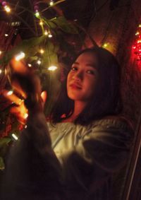 Portrait of teenage girl in illuminated christmas tree