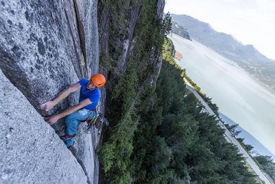 Man lead climbing granite squamish with background view of ocean