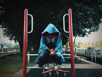 Full length of man sitting on slide at playground