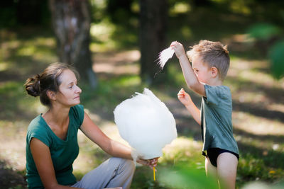Cute european boy son and mom eating cotton candy in the park together, lifestyle