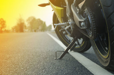 A motorcycle parking on the road right side and sunset.