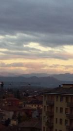 Houses in city against sky during sunset