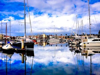 Sailboats moored at harbor against sky