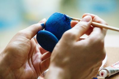 Cropped hands of woman painting toy outdoors