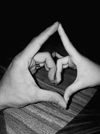 Close-up of woman hand holding heart shape against black background