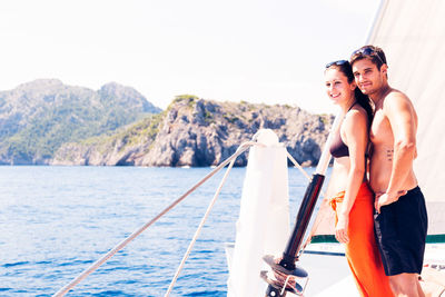 Portrait of young couple standing on boat sailing in sea