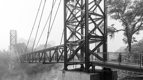 Bridge over river in city against sky