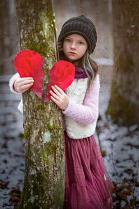 Portrait of cute girl standing on tree trunk