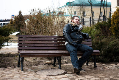 Man sitting on bench against house