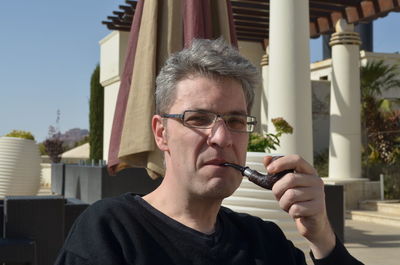 Portrait of mature man smoking pipe outdoors