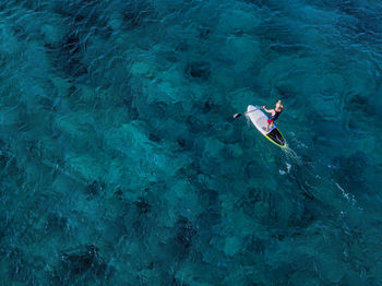 Aerial view of man paddleboarding in blue waters of north male atoll