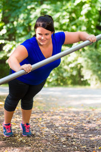 Full length of woman with arms raised against trees