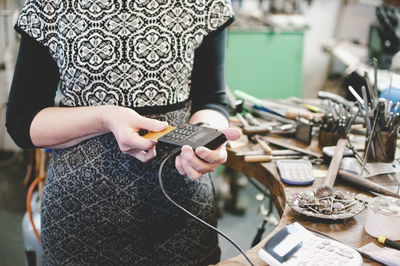 Midsection of woman using mobile phone while sitting on table