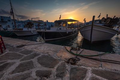 Sailboats moored at harbor against sky during sunset