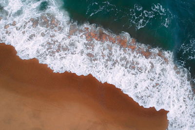 High angle view of sea waves splashing on rocks