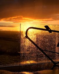 Close-up of silhouette metal by sea against sky during sunset